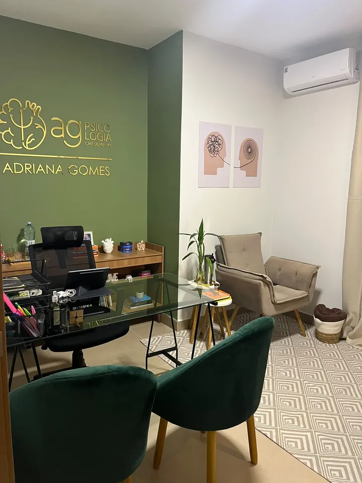 Sala de atendimento da AG Psicologia em São Carlos, com o logo na parede verde e poltronas
